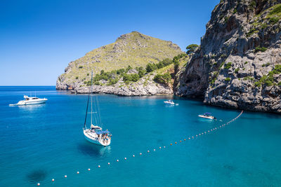 Boats sailing in sea against clear blue sky