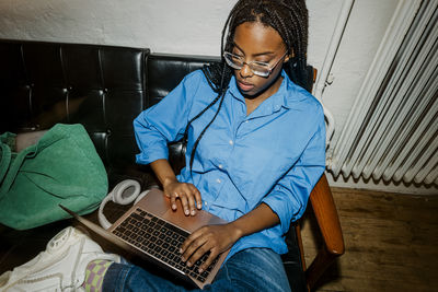 High angle view of female entrepreneur using laptop while sitting on sofa at office