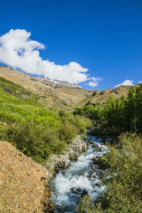 Scenic view of river amidst mountains against blue sky