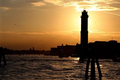 Silhouette of buildings in sea during sunset