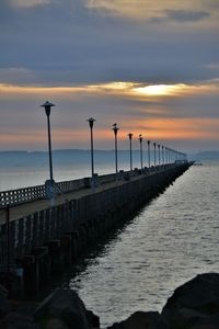 Pier over sea against sky during sunset