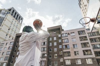 Man throwing basketball in hoop on sunny day