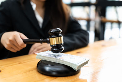 Midsection of woman holding gavel on table