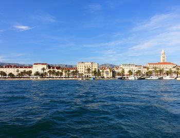 View of buildings by sea against blue sky