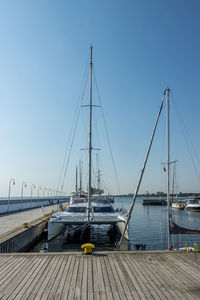 Sailboats moored at harbor against clear blue sky