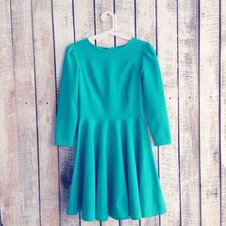 Turquoise dress hanging from wooden wall
