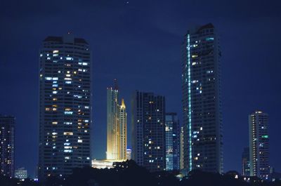 Illuminated buildings in city against sky at night