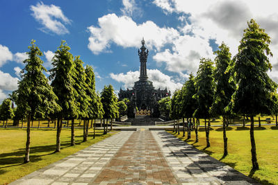View of trees in city against cloudy sky