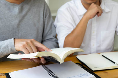 Midsection of man reading book on table