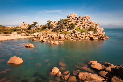 Scenic view of sea by rocks against sky