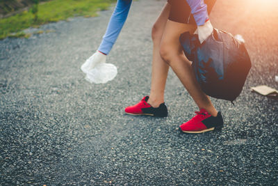 Low section of woman collecting garbage on road