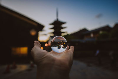 Midsection of person holding crystal ball against building