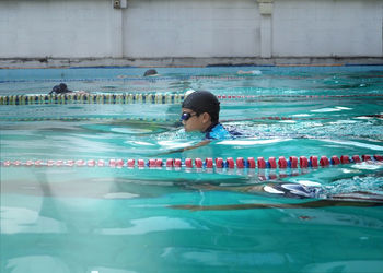 Side view of boy swimming in pool