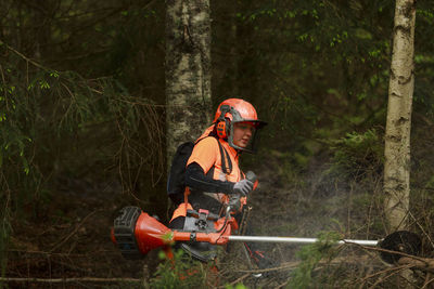 Female lumberjack cutting log in forest