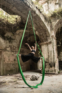 Full length of woman exercising against old building