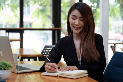 Young woman using phone while sitting on table