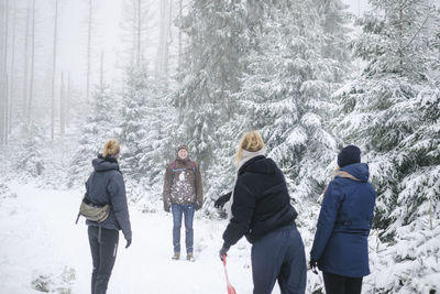 Rear view of people walking on snow covered land