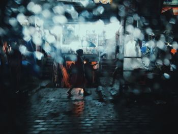 People walking on wet street in city during rainy season