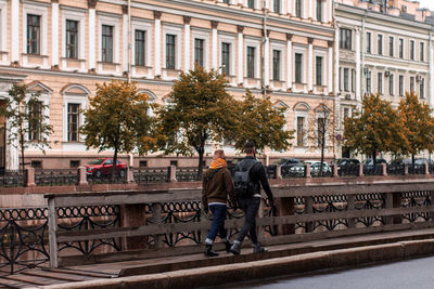 Rear view of people walking against building in city