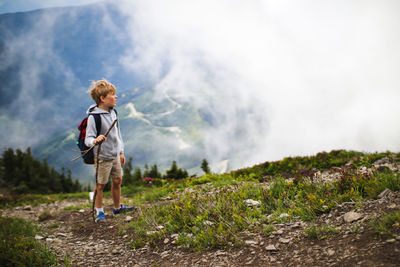 Full length of boy with backpack looking at view on mountain