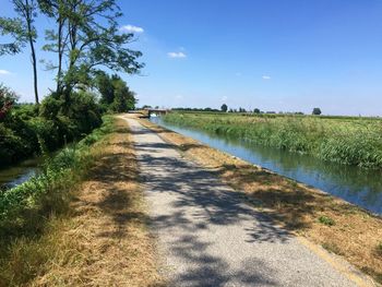 Road amidst field against sky