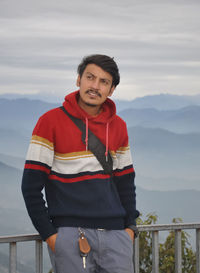 A good looking young guy looking up while standing against the background of mountains