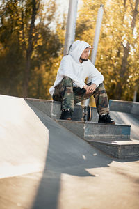 Full length of man with skateboard sitting on steps