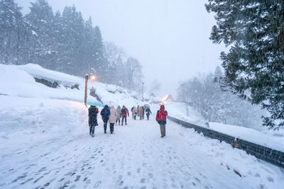 Rear view of people walking on snow covered landscape