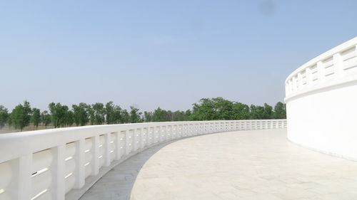 Footpath by wall against clear blue sky