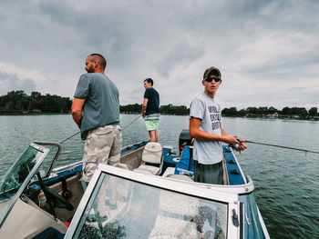 Men standing on boat in sea against sky