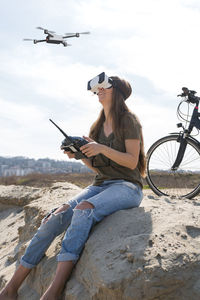 Young woman flying a drone with remote controller and virtual reality goggles
