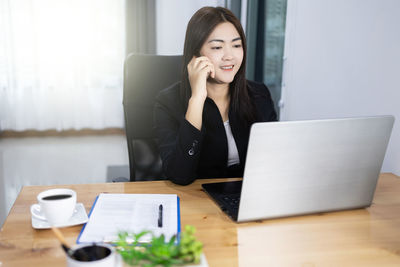 Young woman using mobile phone at table