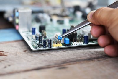 Cropped hand of technician repairing mother board at work shop