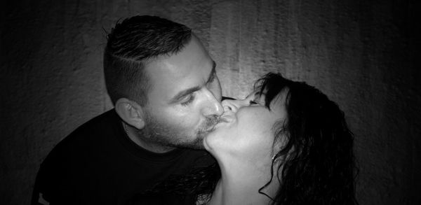 Portrait of couple kissing against wall