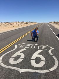 Portrait of man kneeling by marking on road