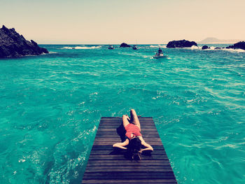 Man sitting in sea against sky