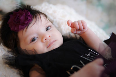 Close-up portrait of cute baby girl on bed at home