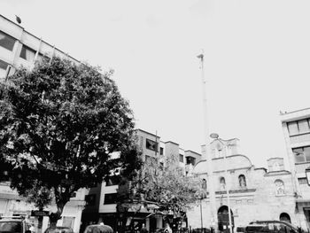 Low angle view of trees and buildings against clear sky