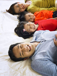 High angle portrait of happy family lying on mattress at home