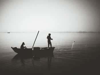 Silhouette fishermen fishing in sea against sky
