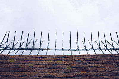 Low angle view of fence on landscape against sky