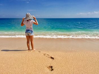 Woman standing at beach against sky