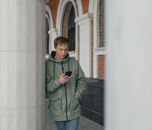 Full length of young man looking through mobile phone