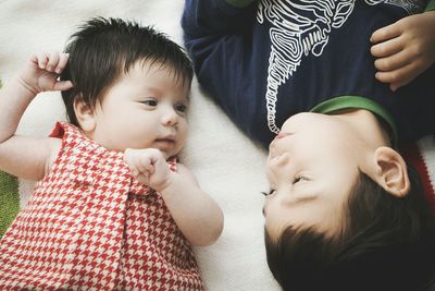 High angle view of siblings lying on bed at home