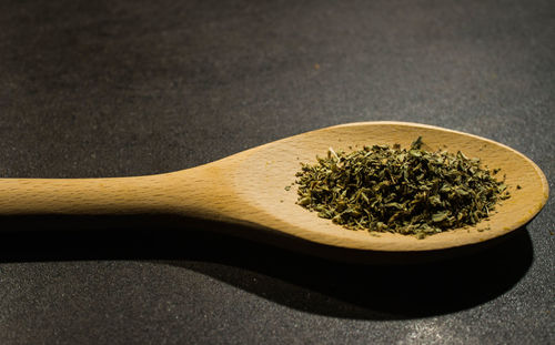 Close-up of dry leaves in wooden spoon on table