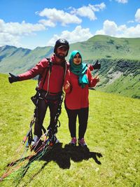 Portrait of couple gesturing peace sign while standing on mountain