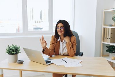 Young woman using mobile phone while sitting on table