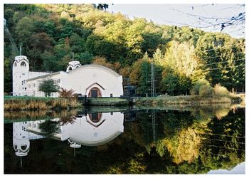 Built structure by lake against trees and plants