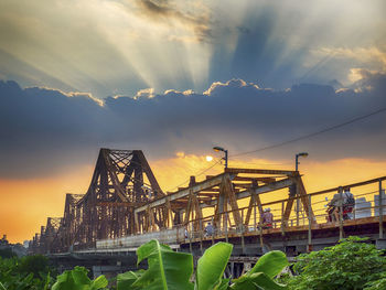 Low angle view of bridge against cloudy sky during sunset