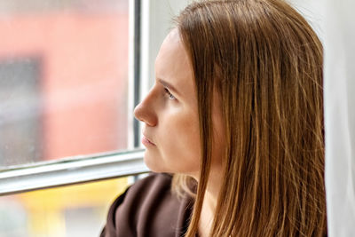 Portrait of a young pensive woman sitting by the window. close-up.